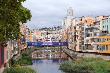 Esta imagen de Girona tan bella como histórica muestra el Puente de las Pescaderías Viejas, sobre el río Onyar, con una pancarta en la que puede leerse 'Territorio de Champions' entre los escudos del Girona Fútbol Club. La ciudad se engalanó para vivir el estreno en casa del Club en la Champions League ante el Feyenoord holandés.  