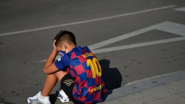 A kid sporting Barcelona&#039;s Argentinian forward Lionel Messi&#039;s jersey sits on the pavement outside the Barcelona&#039;s Ciutat Esportiva Joan Gamper in Sant Joan Despi waiting for the arrival of Barcelona players to undergo a medical test for COV