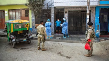 Health Ministry workers escorted by soldiers speak with a resident in the Ate district, on the eastern outskirts of Lima, on February 23, 2021, where residents are checked and have tests to discard COVID-19 done door to door. (Photo by ERNESTO BENAVIDES / AFP)