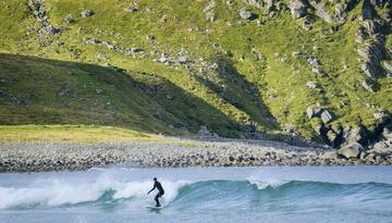 Un surfista monta una ola en el agua de la playa Unstad en la Islas Lofoten, en el Círculo Ártico.