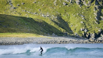 Un surfista monta una ola en el agua de la playa Unstad en la Islas Lofoten, en el Círculo Ártico.