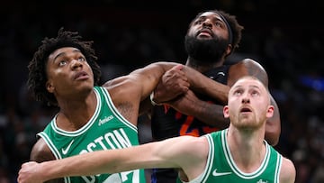 Mitchell Robinson, defendido por dos jugadores de los Celtics en la lucha por un rebote.