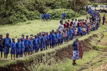 Los estudiantes hacen fila junto a la carretera para ver el coche fúnebre que transporta el ataúd del difunto corredor de maratón Kelvin Kiptum.