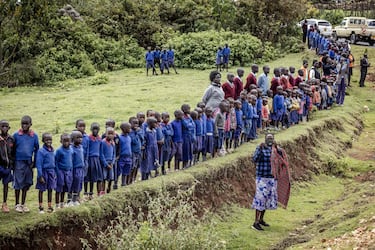Los estudiantes hacen fila junto a la carretera para ver el coche fúnebre que transporta el ataúd del difunto corredor de maratón Kelvin Kiptum.