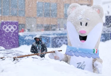 Tina, la mascota olímpica de invierno, ayuda a despejar la nieve de la pista antes de las semifinales de velocidad femenina de esquí de montaña.