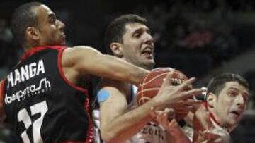 El alero del Manresa Adam Hanga (izq) y el pivot Josh Asselin (d), intentan arrebatar el balón al ala-pivot del Real Madrid Nikola Mirotic, durante el partido correspondiente a la vigésimo primera jornada de la Liga ACB disputado en el Palacio de los Deportes de Madrid.