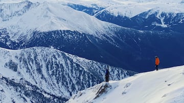 El pic del Comapedrosa, Andorra, nevado, con dos esquiadores en la cima.