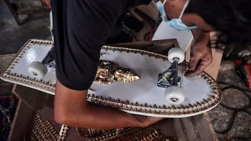 This photo taken on March 19, 2021 shows an employee from the Burapha coffin shop fitting wheels on a skateboard, made from wood used for coffins, in Bangkok. (Photo by Lillian SUWANRUMPHA / AFP)