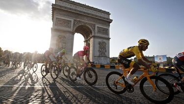 Paris (France).- (FILE) Colombia's Egan Bernal (R) of Team Ineos wears the overall leader's yellow jersey as he passes with the pack by the Arc de Triomphe during the 21st and final stage of the 106th edition of the Tour de France cycling race over 128km