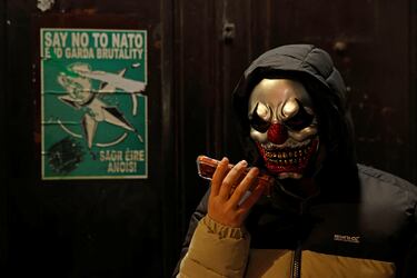 Un hombre con mascarilla habla por teléfono la noche de Halloween, en Dublín, Irlanda.