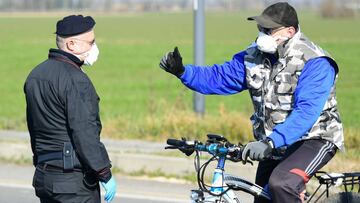 Un carabinieri habla con un hombre que rueda en bicicleta en los alrededores de Castiglione d&#039;Adda, uno de los pueblos de Italia aislados por el brote de coronavirus.