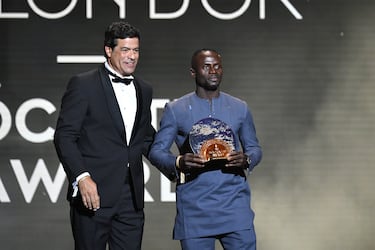 Sadio Mané (der.) recibe el Trofeo Sócrates al jugador más comprometido con proyectos sociales y benéficos de manos de Rai (izq.) durante la ceremonia del Balón de Oro en el Théâtre du Châtelet de París, el 17 de octubre de 2022.