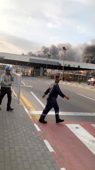 Trabajadores evacúan el área alrededor de la refinería mientras el humo se eleva tras un presunto ataque con drones iraníes, en Ras Tanura, Arabia Saudita.