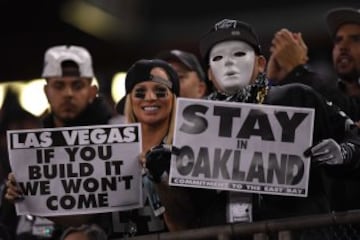 Dos fans de los Raiders sostienen sendos carteles durante el encuentro contra los Broncos. El de la derecha reza "Quedaos en Oakland". El de la izquierda pone "Ya sé que mi amigo da miedete porque va en plan Michael Myers, pero va, quedaos, que no hace na