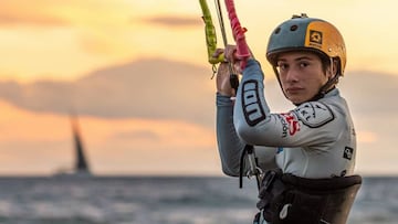 Rafael Montero, ganador de la categoría Junior del Video King SKL 2021, mirando a cámara agarrado a su cometa, con un velero y unas nubes de fondo, al atardecer, sobre el mar.