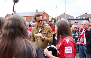 El actor y copropietario del Wrexham, Ryan Reynolds, habla con los aficionados fuera del estadio antes del partido.