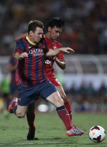 Leo Messi se disputa un balón con Atit Daosawang