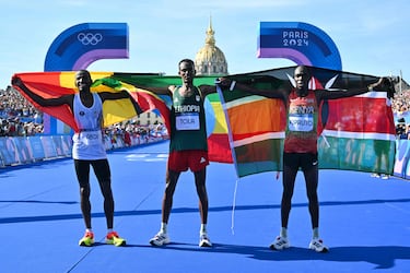 Winner Ethiopia's Tamirat Tola (C), second placed Belgium's Bashir Abdi (L) and third placed Kenya's Benson Kipruto celebrate after the men's marathon of the athletics event at the Paris 2024 Olympic Games at Invalides in Paris on August 10, 2024. (Photo by Andrej ISAKOVIC / AFP)