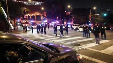 A man in a car uses his mobile phone as members of law enfocement stand guard on a road after curfew, as protests against federal immigration sweeps continue, in downtown Los Angeles, California, U.S. June 10, 2025. REUTERS/Leah Millis