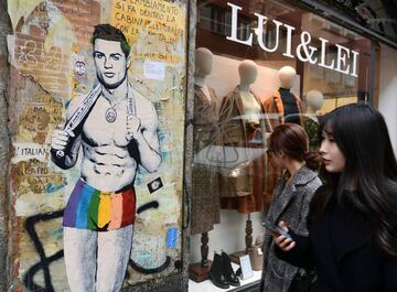 People walk past a new mural by Italian street artist TvBoy, entitled "Il Segreto di Cristiano".