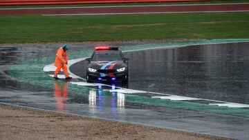 A steward talks to the driver of a test car on the wet track as the start of the MotoGP race is delayed due to rain during the motorcycling British Grand Prix at Silverstone circuit in Northamptonshire, southern England, on August 26, 2018. (Photo by Oli SCARFF / AFP)