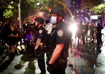 Police officers look on as demonstrators march along a street in protest against the death in Minneapolis police custody of George Floyd, in New York City, New York, U.S., 5 June 2020.