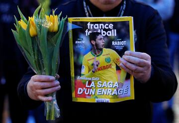 A man holds a sports magazine and yellow tulips as fans gather in Nantes' city center after news that newly-signed Cardiff City soccer player Emiliano Sala was missing after the light aircraft he was travelling in disappeared between France and England th