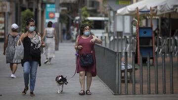 Imagen de varias personas caminando con mascarillas por las calles de L'Hospitalet, donde se ha producido un brote de coronavirus.