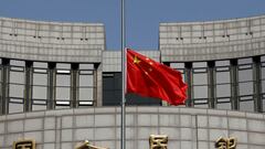 FILE PHOTO: The Chinese national flag flies at half-mast at the headquarters of the People's Bank of China, the central bank (PBOC), as China holds a national mourning for those who died of the coronavirus disease (COVID-19), on the Qingming tomb-sweeping festival in Beijing, China April 4, 2020.  REUTERS/Carlos Garcia Rawlins/File Photo