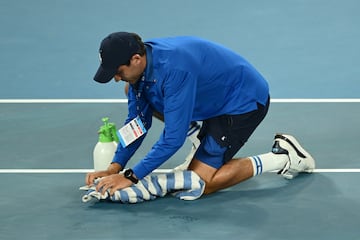 Un miembro del staff limpia la cancha en el partido de cuartos de final de individuales masculinos entre Carlos Alcaraz y Novak Djokovic.