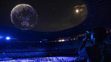 Un hombre fotografía los drones que forman un globo sobre el cielo durante la ceremonia de apertura de los Juegos Olímpicos de Tokio.
