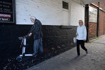 A woman walks past a graffiti mural by street artist Rachel List paying tribute to Britain's NHS (National Health Service) staff battling the COVID-19