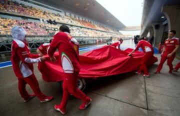 Los mecánicos de Ferrari protegen el coche de la lluvia.