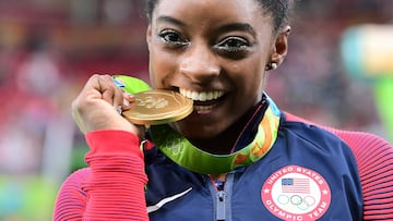 (FILES) US gymnast Simone Biles celebrates with her gold medal after the women's individual all-around final of the Artistic Gymnastics at the Olympic Arena during the Rio 2016 Olympic Games in Rio de Janeiro on August 11, 2016. In Rio, US' Simone Biles became the fourth gymnast in the history of the Games to win four gold medals in a single edition. (Photo by Emmanuel DUNAND / AFP)