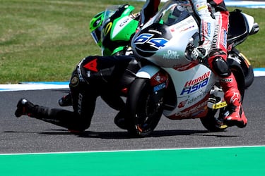 El piloto italiano Mattia Casadei (de negro) se cae durante la primera práctica de la categoría de Moto2 del GP de Australia justo delante del neerlandés Bo Bendsneyder (64). A pesar de la espectacularidad de la acción, ninguno de los dos corredores sufrió daños y pudieron completar las sesiones de entrenamientos.