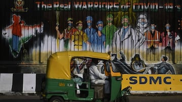 An auto rickshaw crosses a mural reading 'The Real Warriors of COVID-19' after the government eased a nationwide lockdown imposed as a preventive measure against the Covid-19 coronavirus, in New Delhi on June 9, 2020.