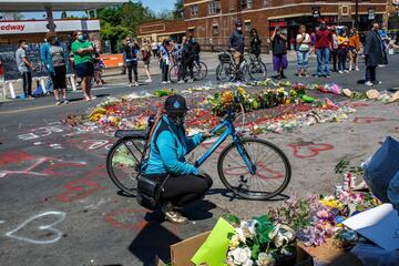 A woman set flowers by a makeshift memorial in honor of George Floyd, who died while in custody of the Minneapolis police, following a day of demonstration in a call for justice on May 30, 2020 in Minneapolis, Minnesota. - Demonstrations are being held across the US after George Floyd died in police custody on May 25. (Photo by Kerem Yucel / AFP)