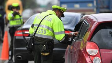 A police officer checks a driver´s document at a checkpoint on a road entering Bogota, on June 18, 2022, a day before the presidential runoff election. - Colombians vote Sunday in a presidential runoff that features promises of radical change in a country saddled with widespread poverty, violence and other woes. After a tense campaign marked by claims of death threats against several candidates, opinion polls have leftist Gustavo Petro and businessman Rodolfo Hernandez neck-and-neck. (Photo by DANIEL MUNOZ / AFP) (Photo by DANIEL MUNOZ/AFP via Getty Images)