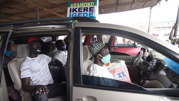 Travellers sit in a minibus while wearing face masks in compliance with measures to curtail the spread of COVID-19 coronavirus following the ease of interstate travels, at the Ojota bus terminal in Lagos, on July 1, 2020. - Bus terminals across the countr