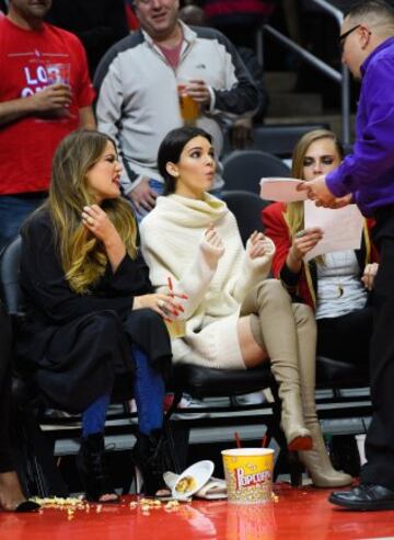 Khloe Kardashian, celebridad y presentadora de radio estadounidense (I) junto a su hermana Kendall Jenner (D), modelo y animadora estadounidense, atienden a un aficionado en el Staples Center.