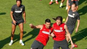 INTENSIDAD. Villa y Filipe Luis luchan por un balón ante la mirada de Simeone en unos de los ejercicios del entrenamiento de ayer.