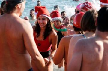 Decenas de ciudadanos participaron este mediodía en el tradicional primer baño del año en la playa de Sant Sebastià del barcelonés barrio de la Barceloneta.