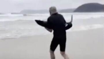 Paul Myles llevando en brazos de regreso al océano a un tiburón que lo estaba pasando mal en la playa de Eastern View, en Great Ocean Road, Victoria (Australia). Enero del 2023.
