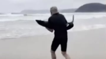 Paul Myles llevando en brazos de regreso al oc&eacute;ano a un tibur&oacute;n que lo estaba pasando mal en la playa de Eastern View, en Great Ocean Road, Victoria (Australia). Enero del 2023. 
