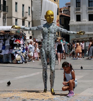 Un ni?o se arrodilla junto a un maniqu que representa al fundador de Amazon, Jeff Bezos, cubierto de billetes falsos, instalado en la Plaza de San Marcos como parte de una parodia del colectivo artstico Konn Artiss, antes de la boda de Bezos y la periodista Lauren Snchez.