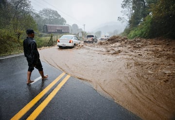 Un residente local observa cómo los automóviles atraviesan un tramo peligroso de carretera inundada después de ayudar a limpiar rocas del agua mientras la tormenta tropical Helene azota, en las afueras de Boone, Carolina del Norte.