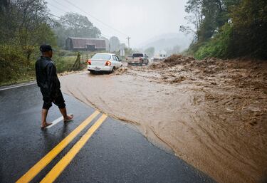 Un residente local observa cómo los automóviles atraviesan un tramo peligroso de carretera inundada después de ayudar a limpiar rocas del agua mientras la tormenta tropical Helene azota, en las afueras de Boone, Carolina del Norte.