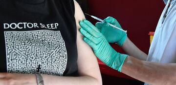 A medical assistant inserts into the arm the needle of a syringe