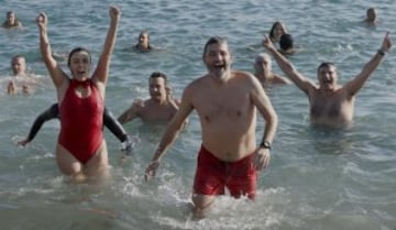 Decenas de ciudadanos participaron este mediodía en el tradicional primer baño del año en la playa de Sant Sebastià del barcelonés barrio de la Barceloneta.