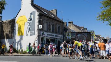 Un mural dedicado a Hinault ayer en su localidad, Yfinniac, con un aficionado vestido como El Tejón para ver el Tour.